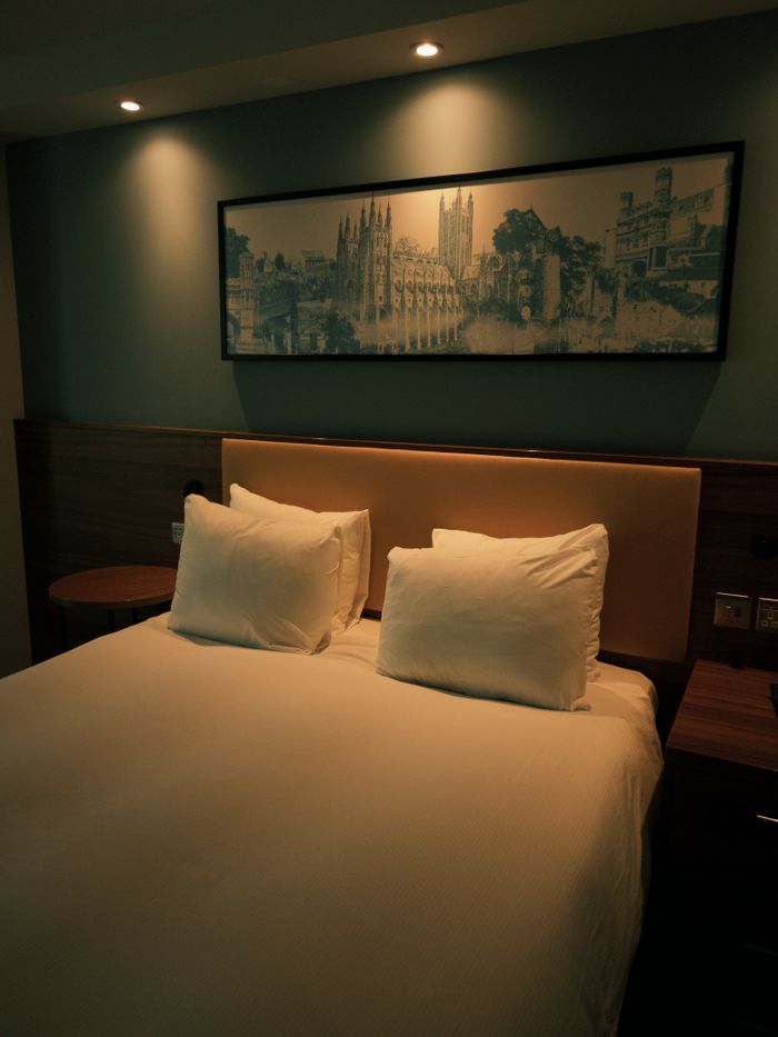 The Art of Drawing Readers In: Your attractive post title goes here Modern hotel room with a double bed, framed artwork, and ambient lighting.